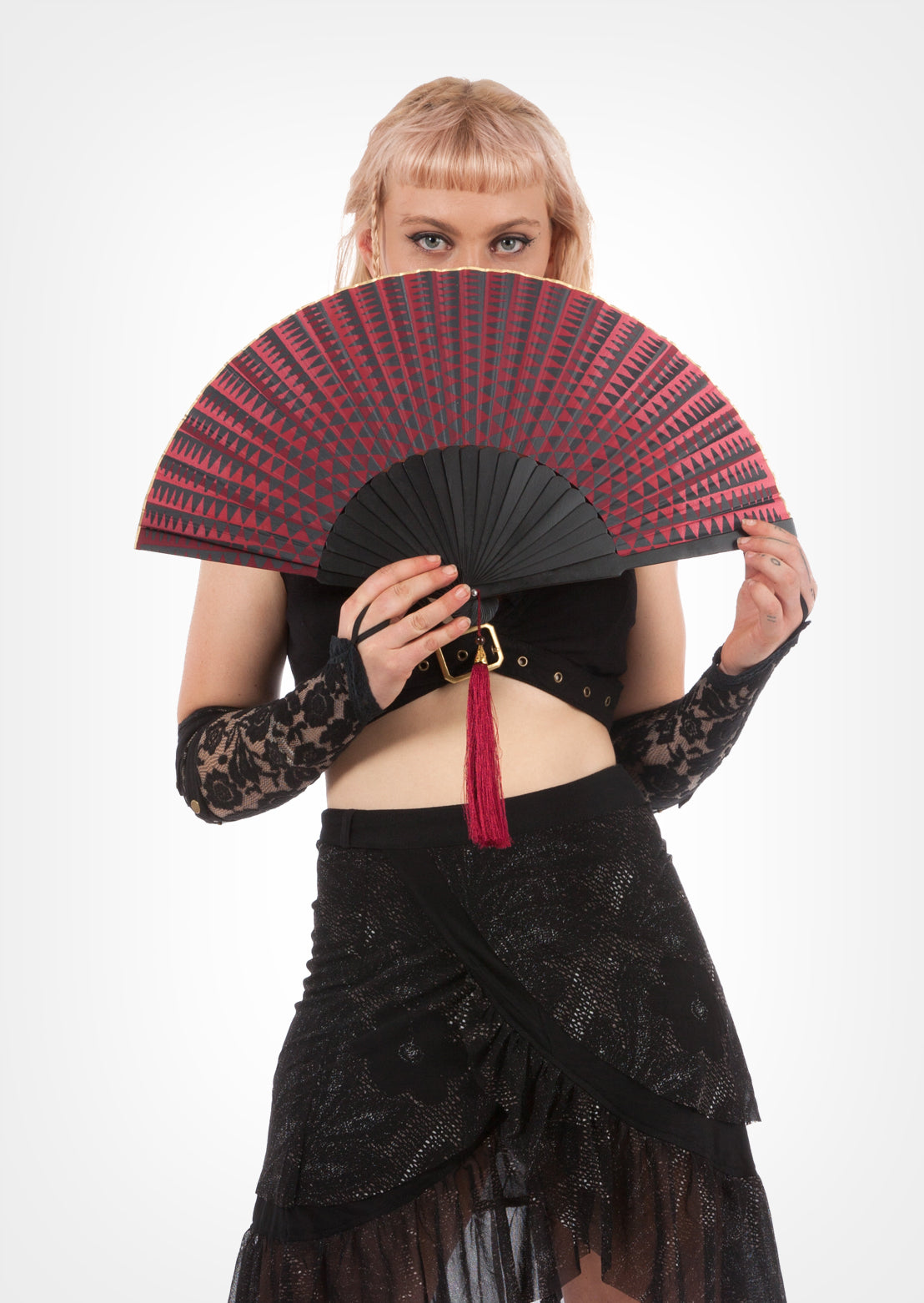 A person holding a fan with a cosmic print, featuring a wooden structure and a fringed edge.